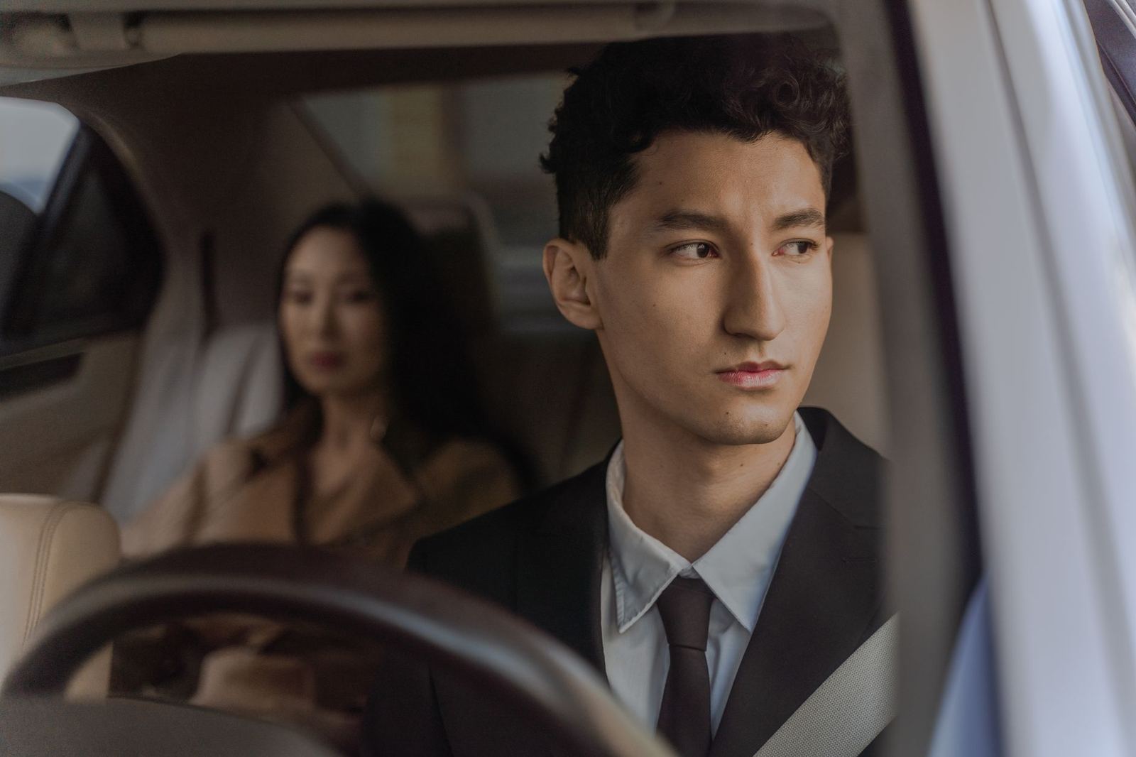 A chauffeur holding the rear door of a sedan at a hotel entrance