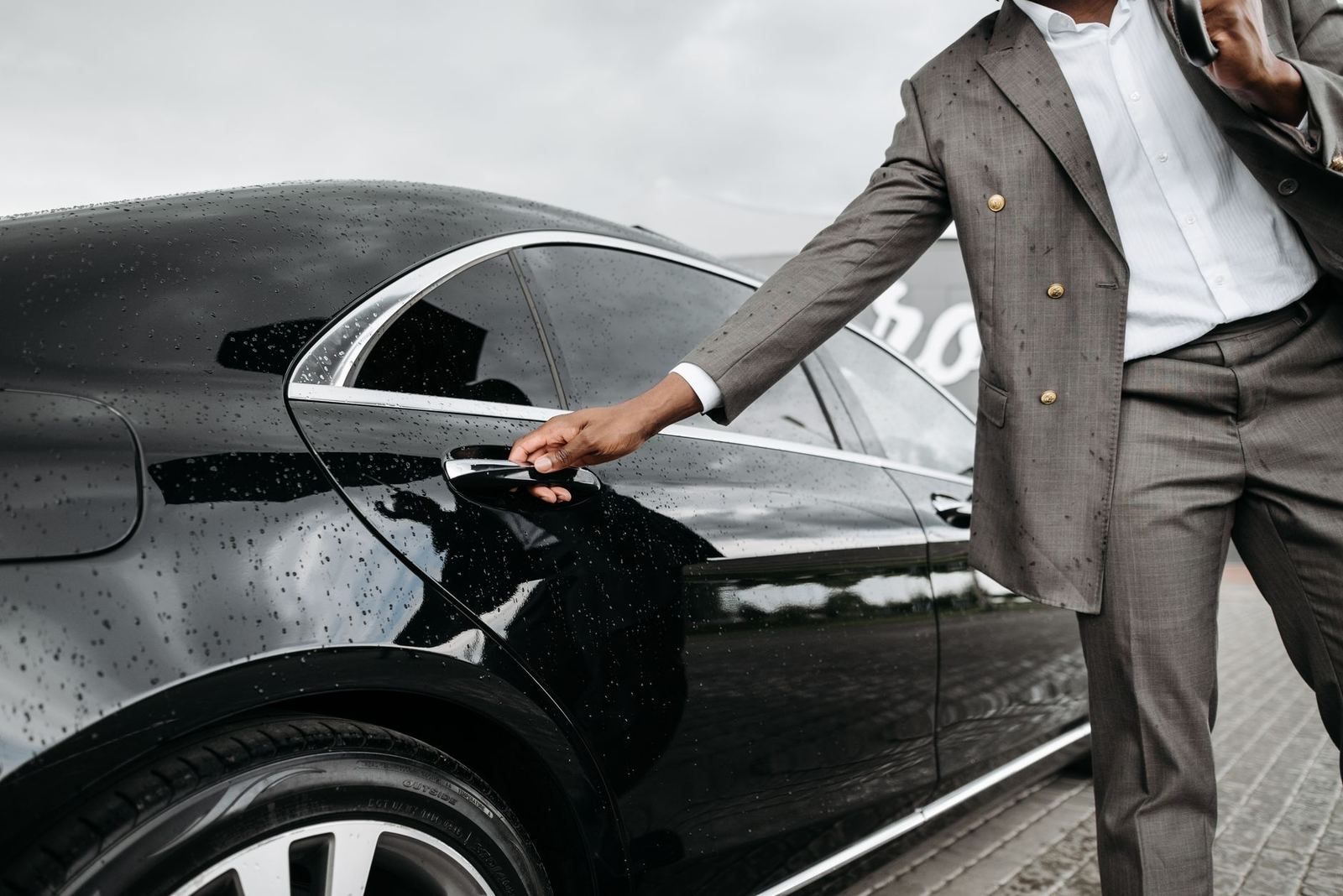A chauffeur opening the rear door of a black car